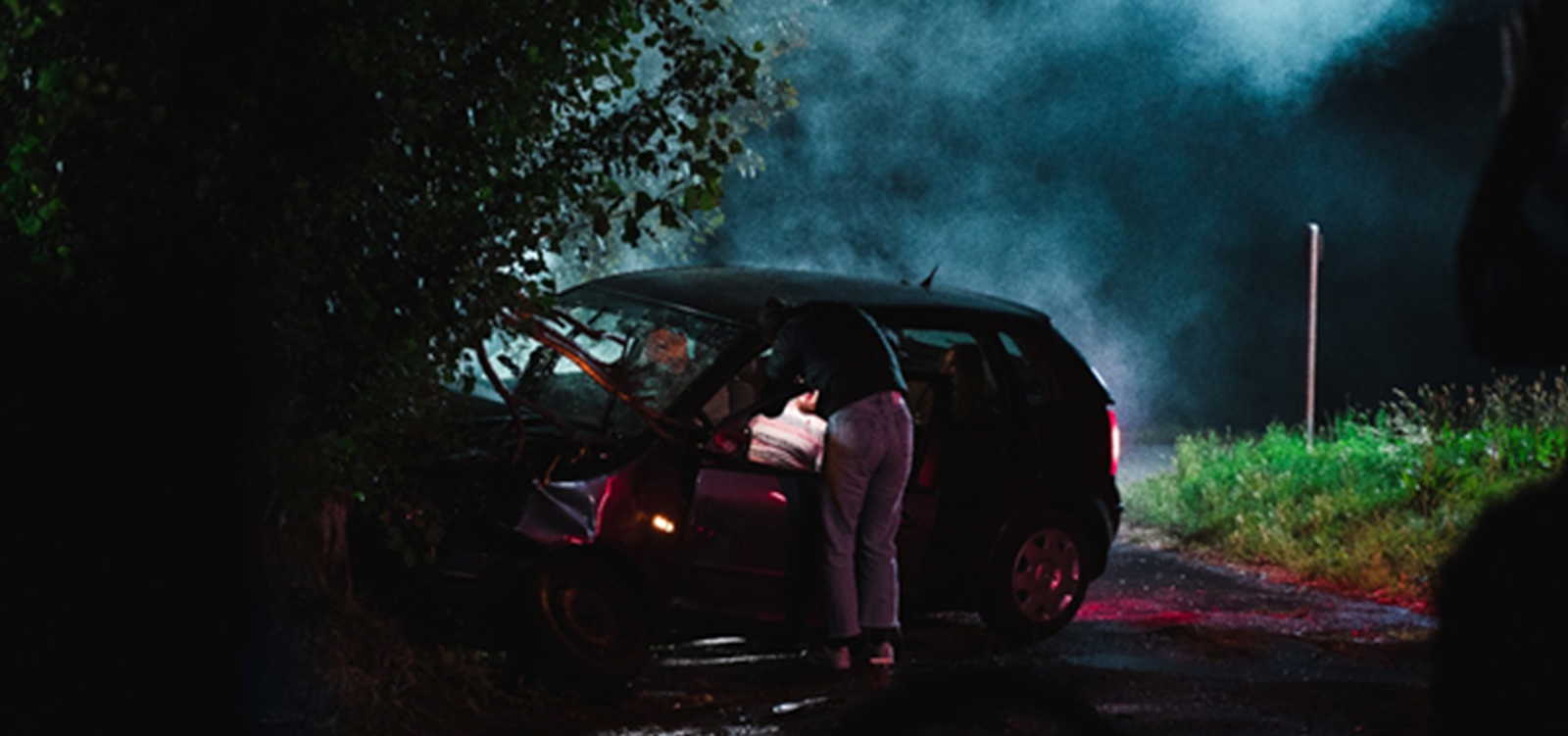 Man looking inside a car that has crashed